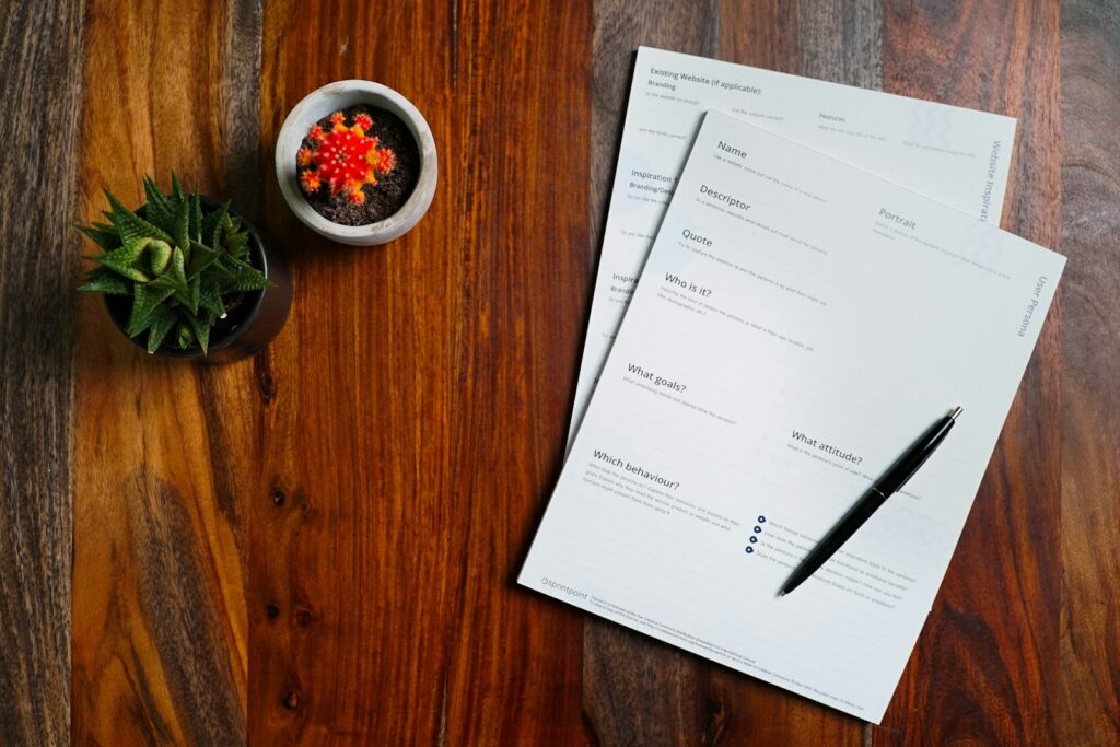Application forms and a pen on a wooden desk
