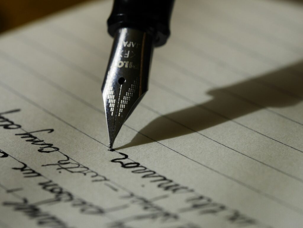 A fountain pen writing by hand on lined paper