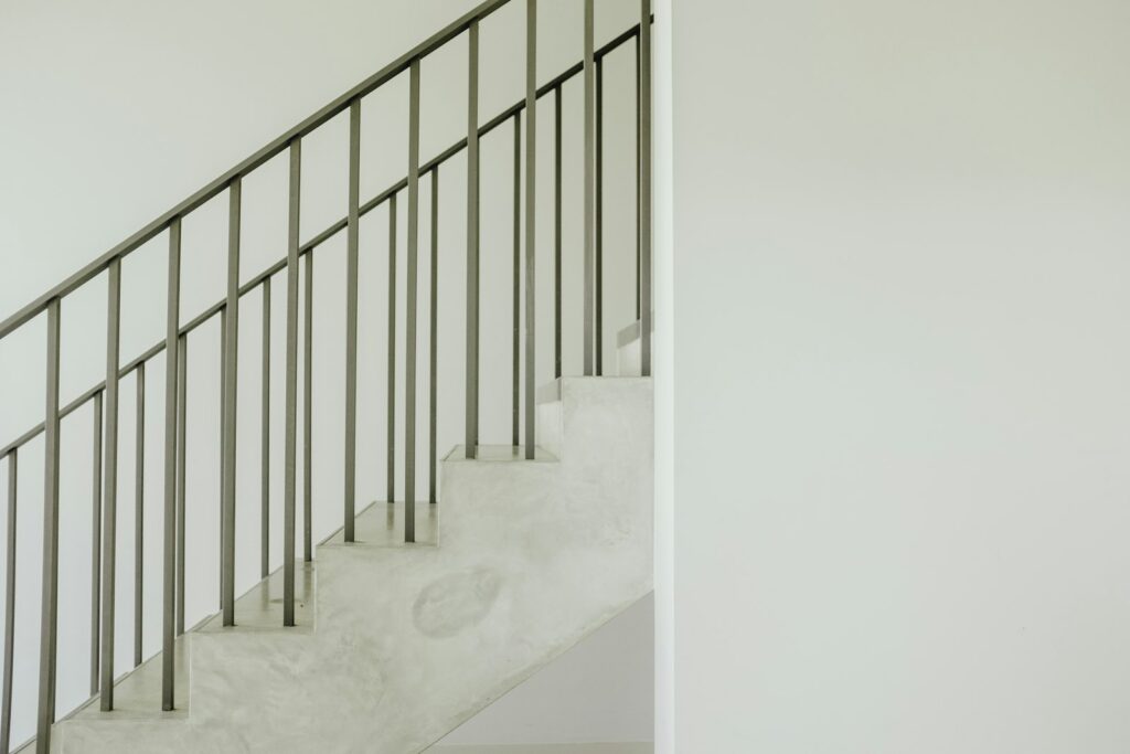 A concrete staircase with a grey steel handrail