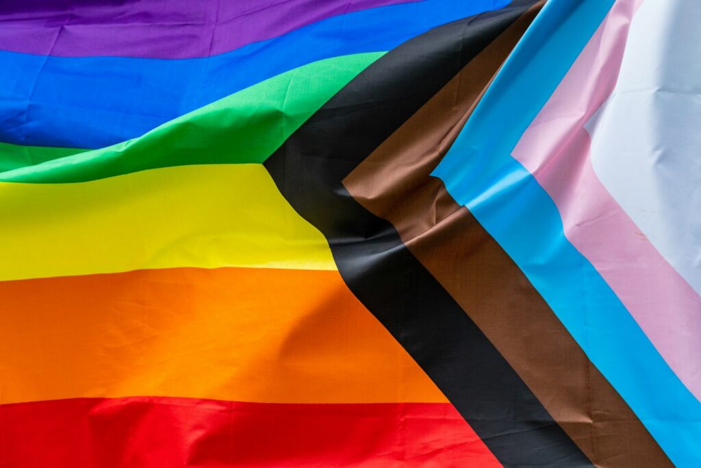 A progress pride flag waving against the sky
