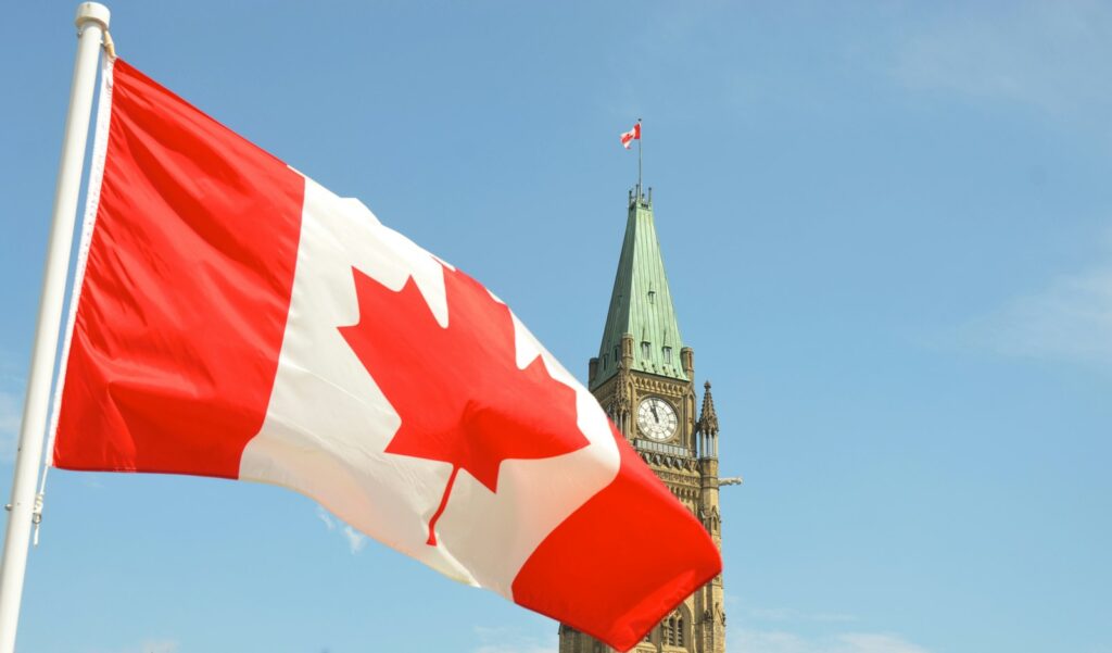 A Canadian flag waving in front of the Peace Tower on Parliament Hill