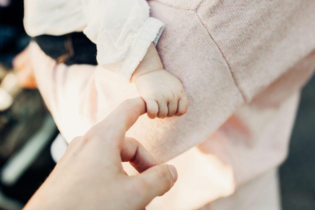A young child’s hand holding a parent’s finger