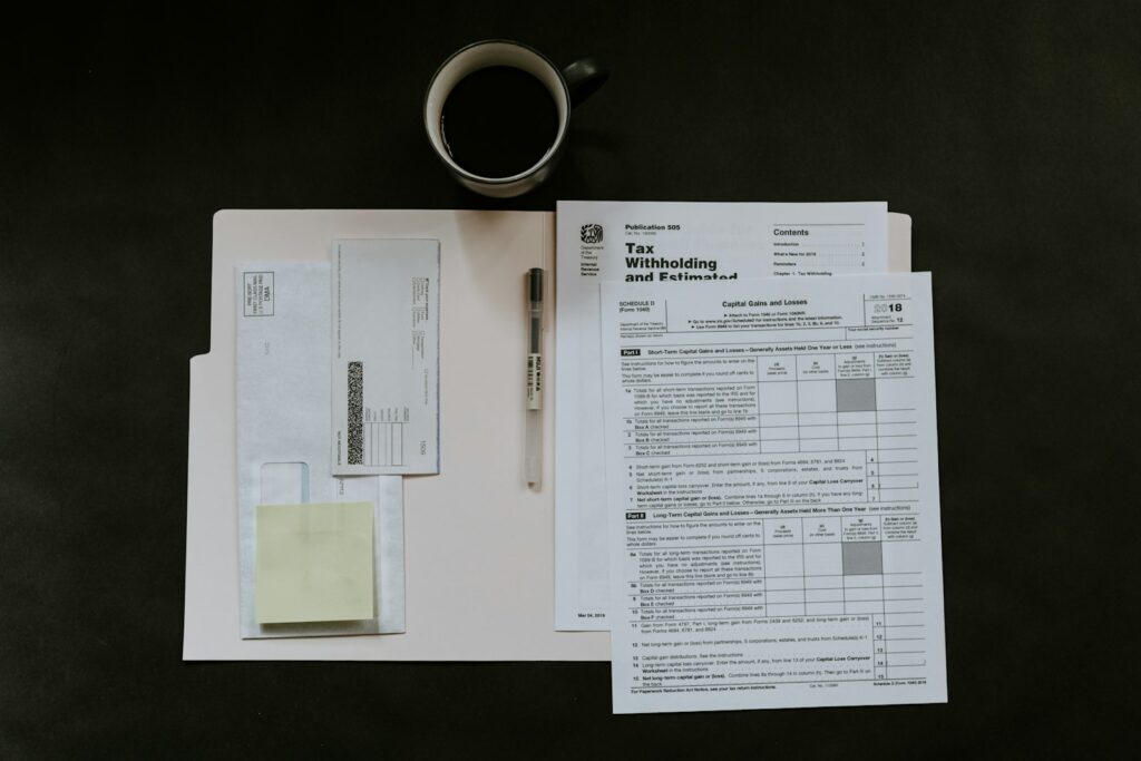 Paper forms, a pen and a coffee mug on a dark desk