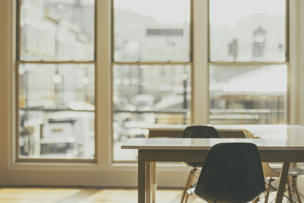 Empty white desks beside a large window in a quiet office