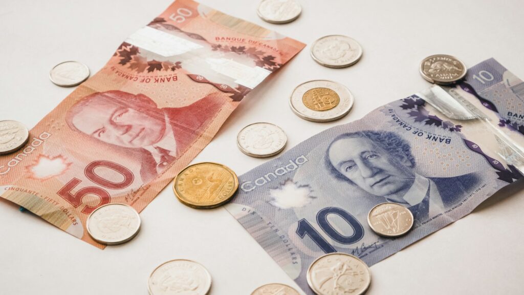 Canadian banknotes and coins on a grey surface