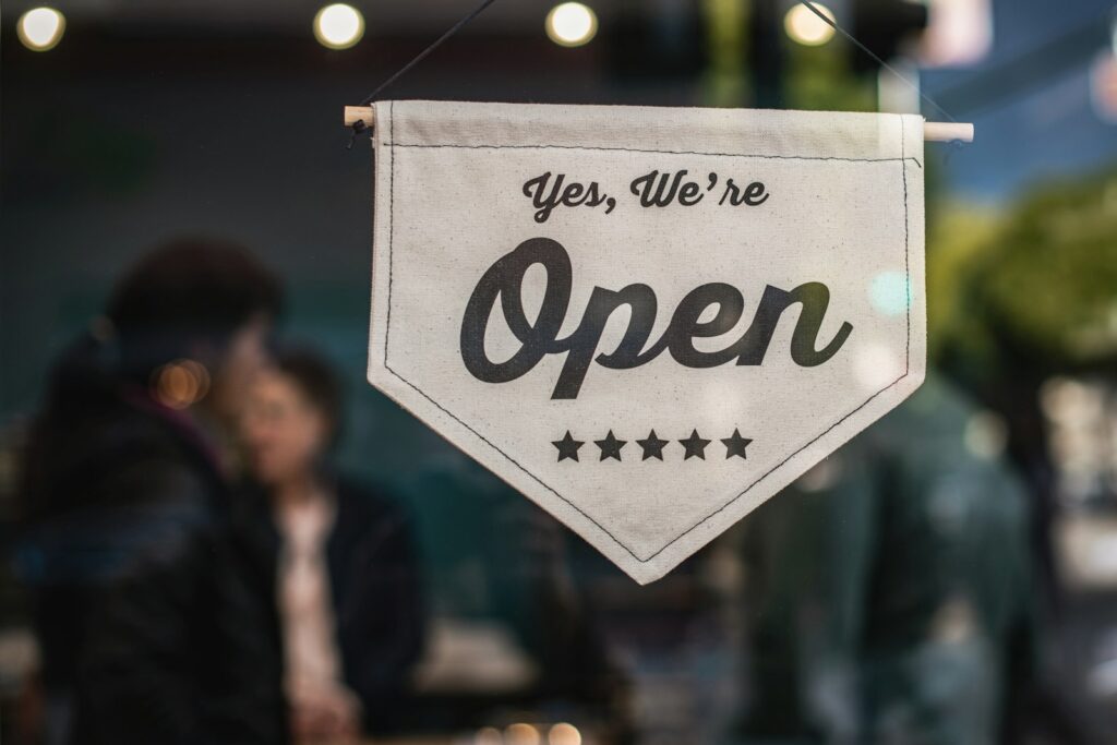 A white “Yes, we’re open” sign hanging in a shop window