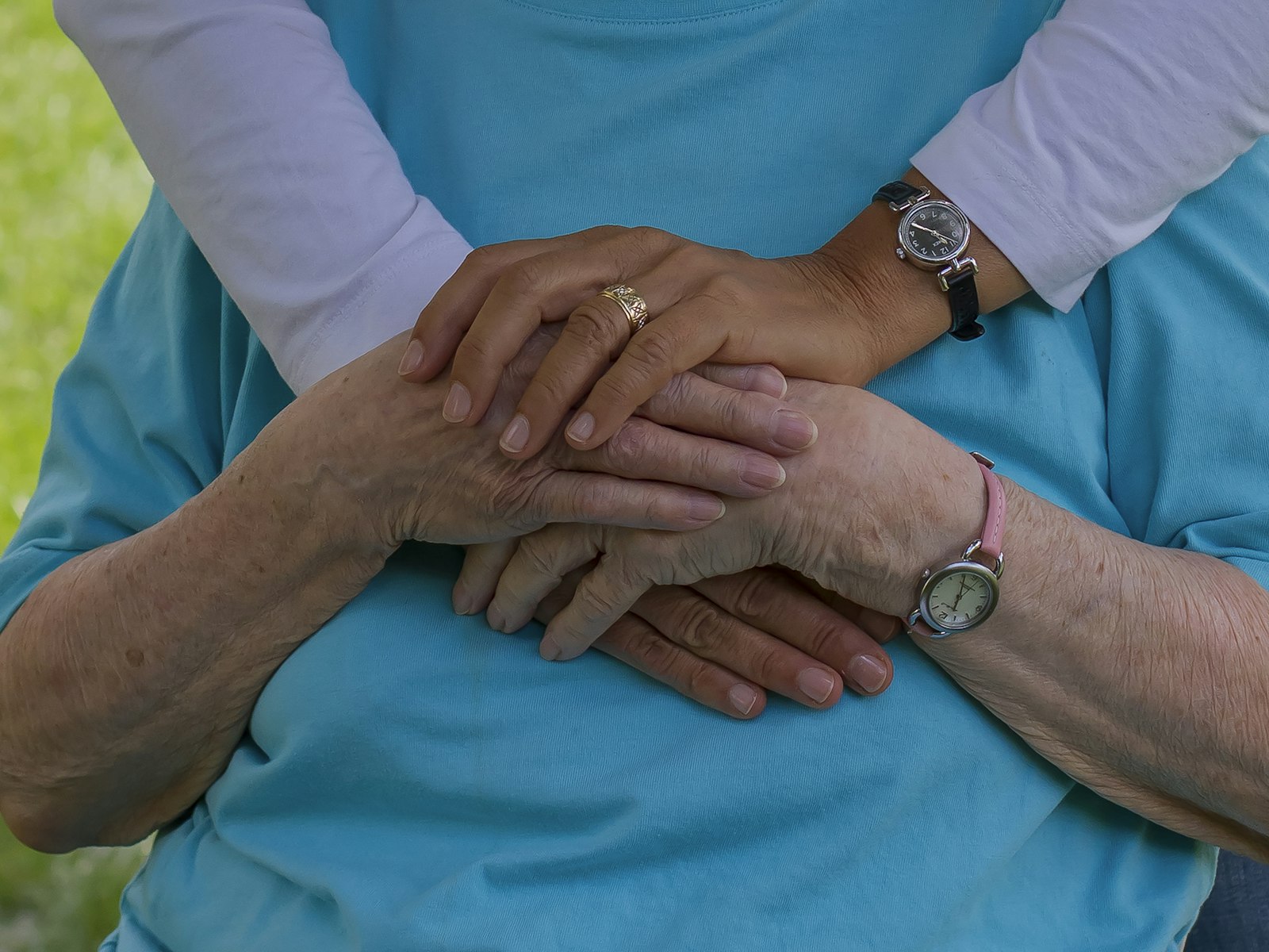 A caregiver holding the hands of an elderly woman