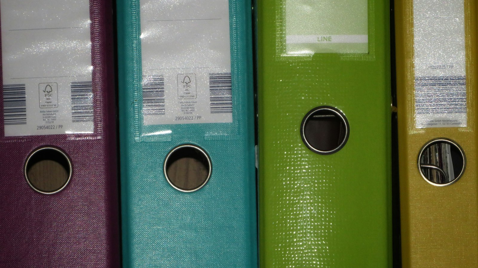 Row of coloured file binders on a shelf