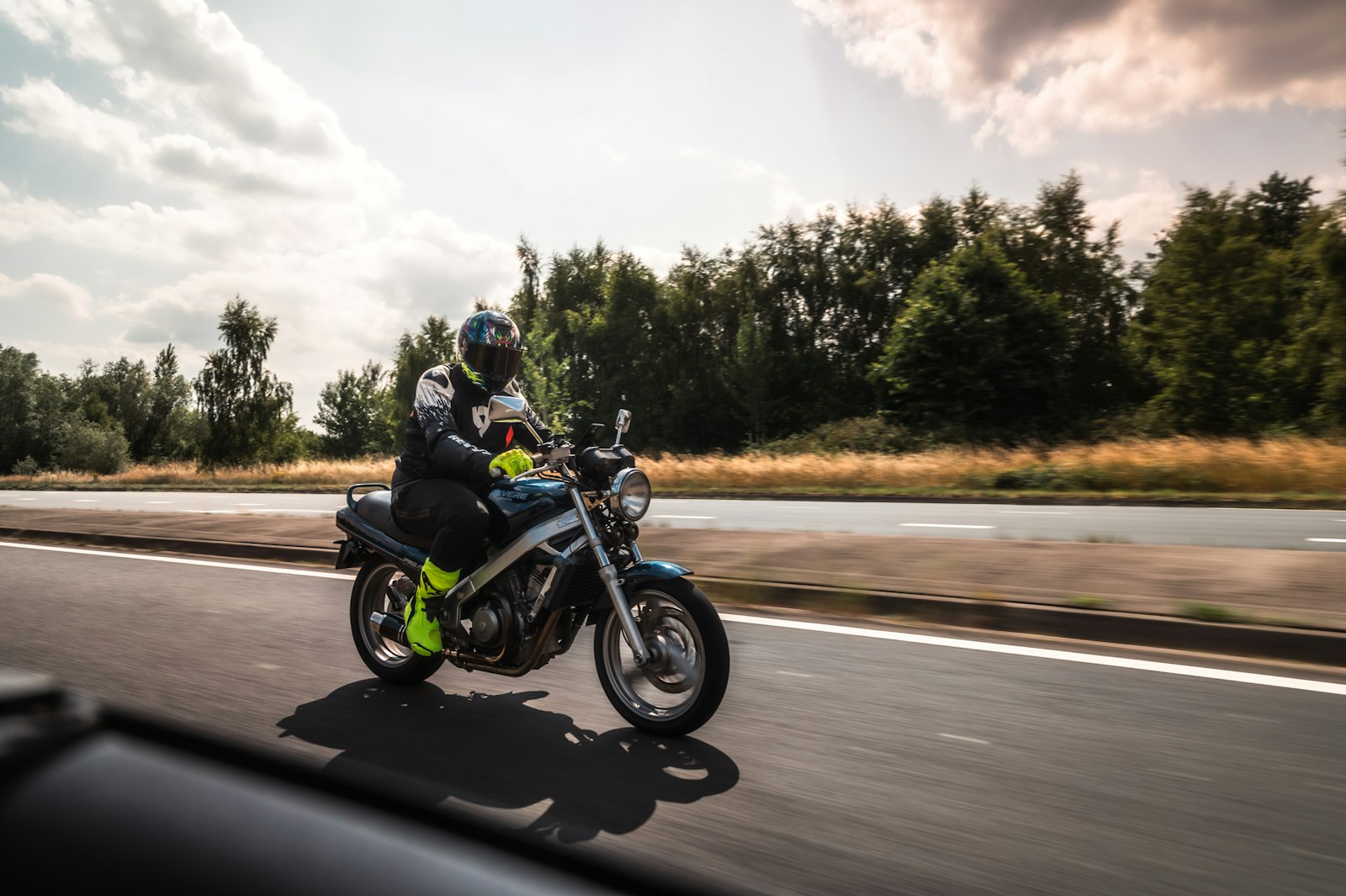 A motorcycle rider in protective gear riding along a highway